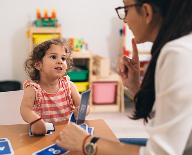 teacher and girl in kindergarten, learning how to correct pronou